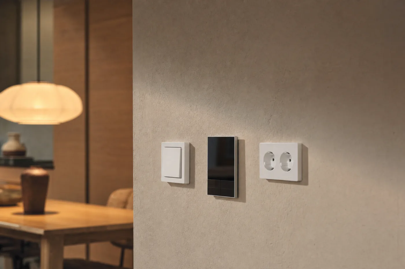 Lichtschalter, Smart-Home-Bedienfeld und Doppelsteckdose an einer verputzten Wand